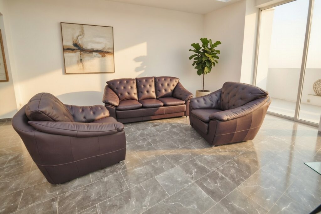 Ciemnobrązowy zestaw skórzanych sof w nowoczesnym salonie z marmurową podłogą i dużymi oknami.